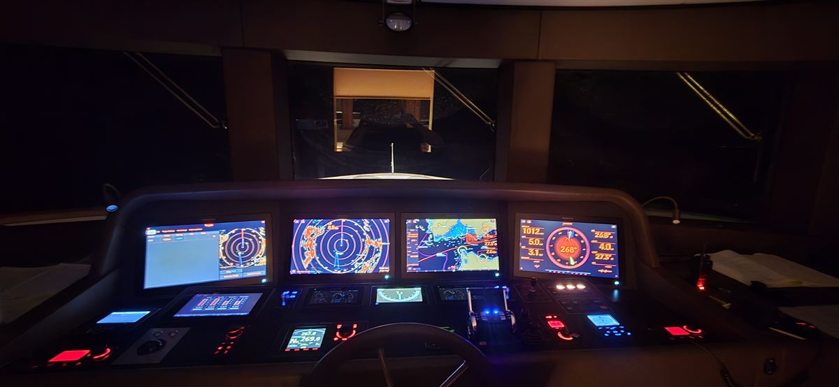 A yacht bridge at night, its navigation screens lit