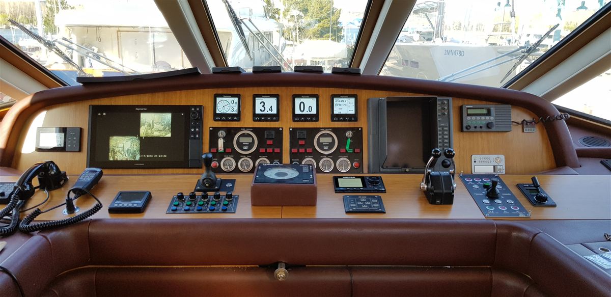 A wood-panelled wheelhouse console with engine instruments and controls