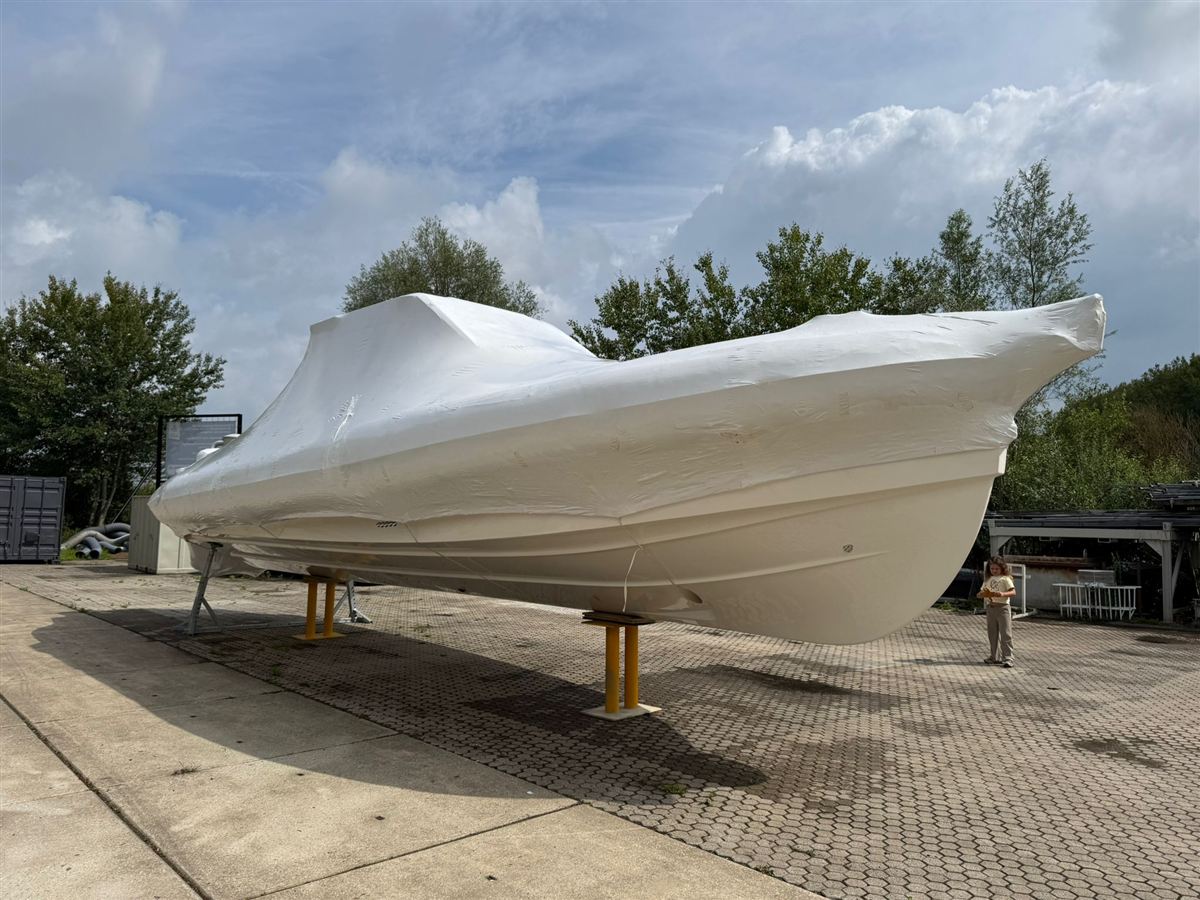 A motor boat shrink-wrapped for the winter, standing ashore