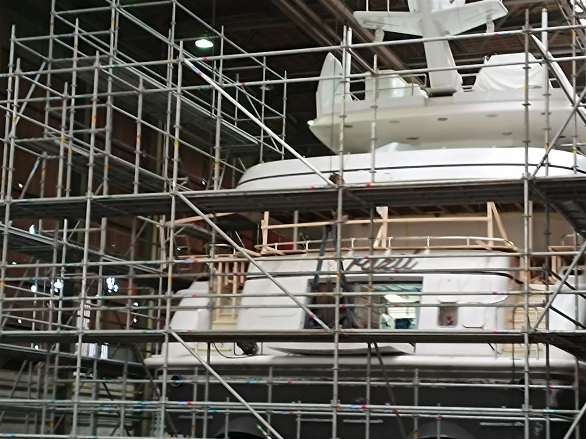 A motor yacht under scaffolding during a refit in a shed