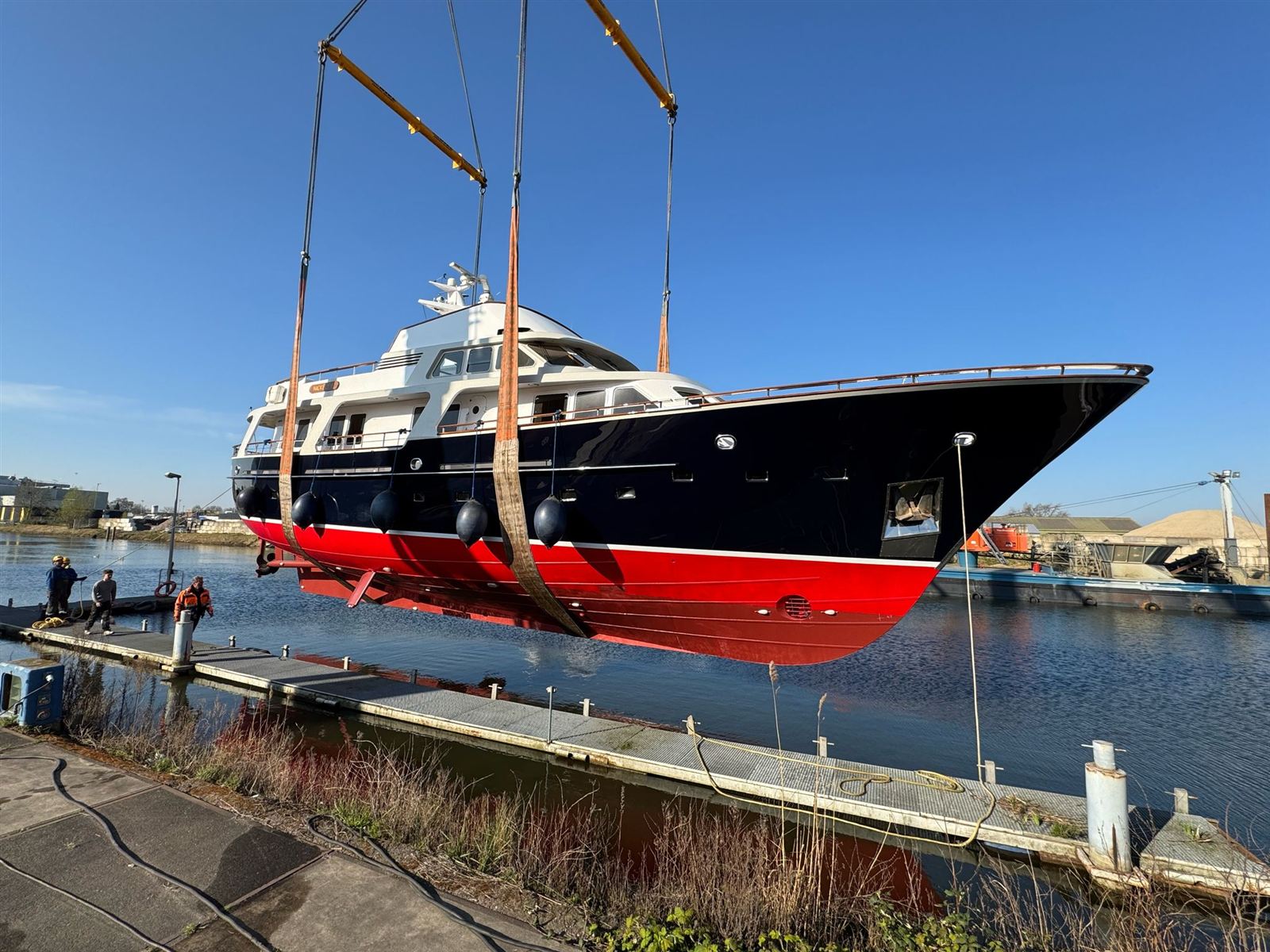 A motor yacht lifted out of the water by two mobile cranes
